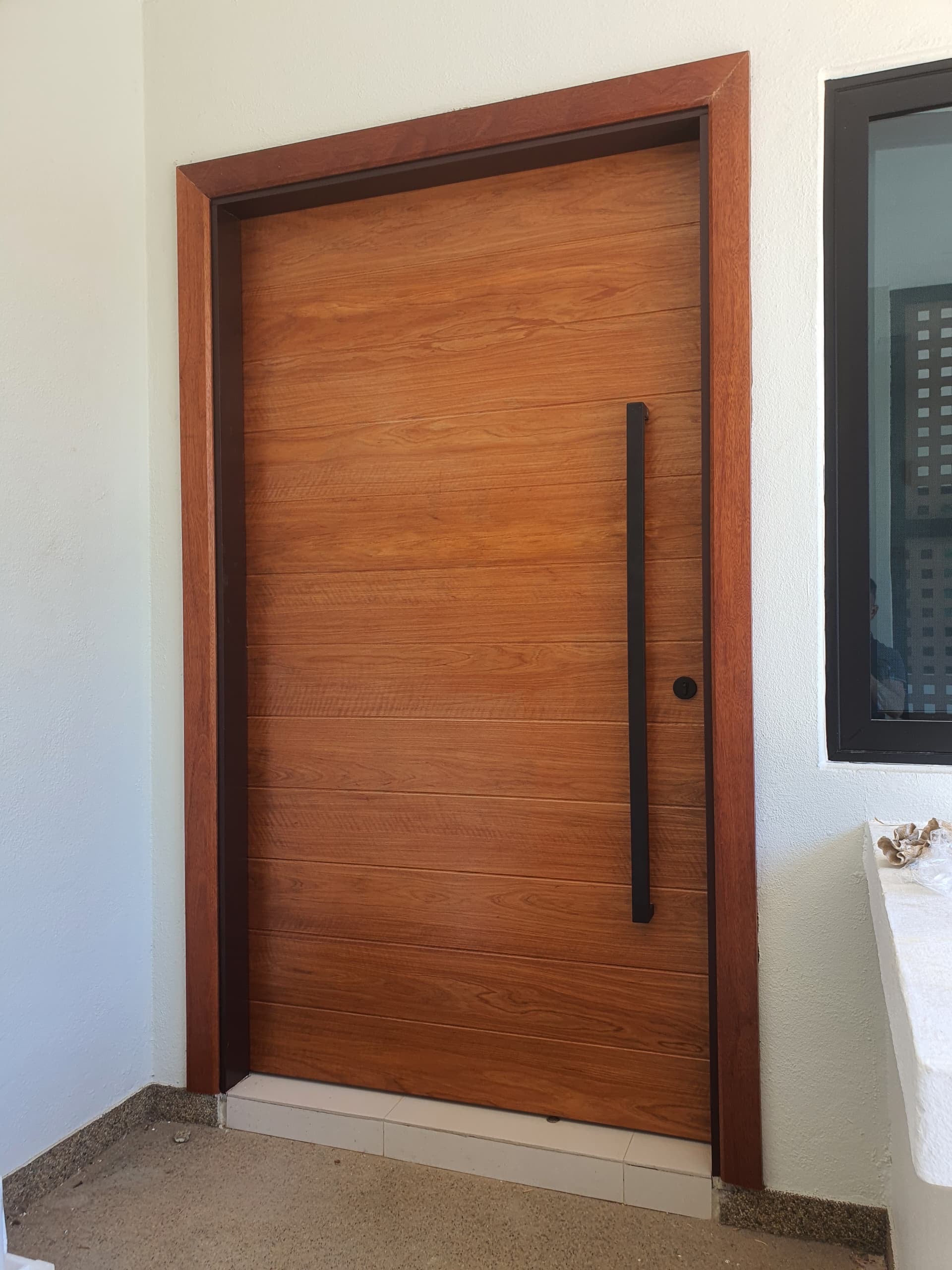 Grade A full solid timber door, frame and architrave made out of nyatoh hardwood with beautiful natural grains, installed at the entrance of a house.