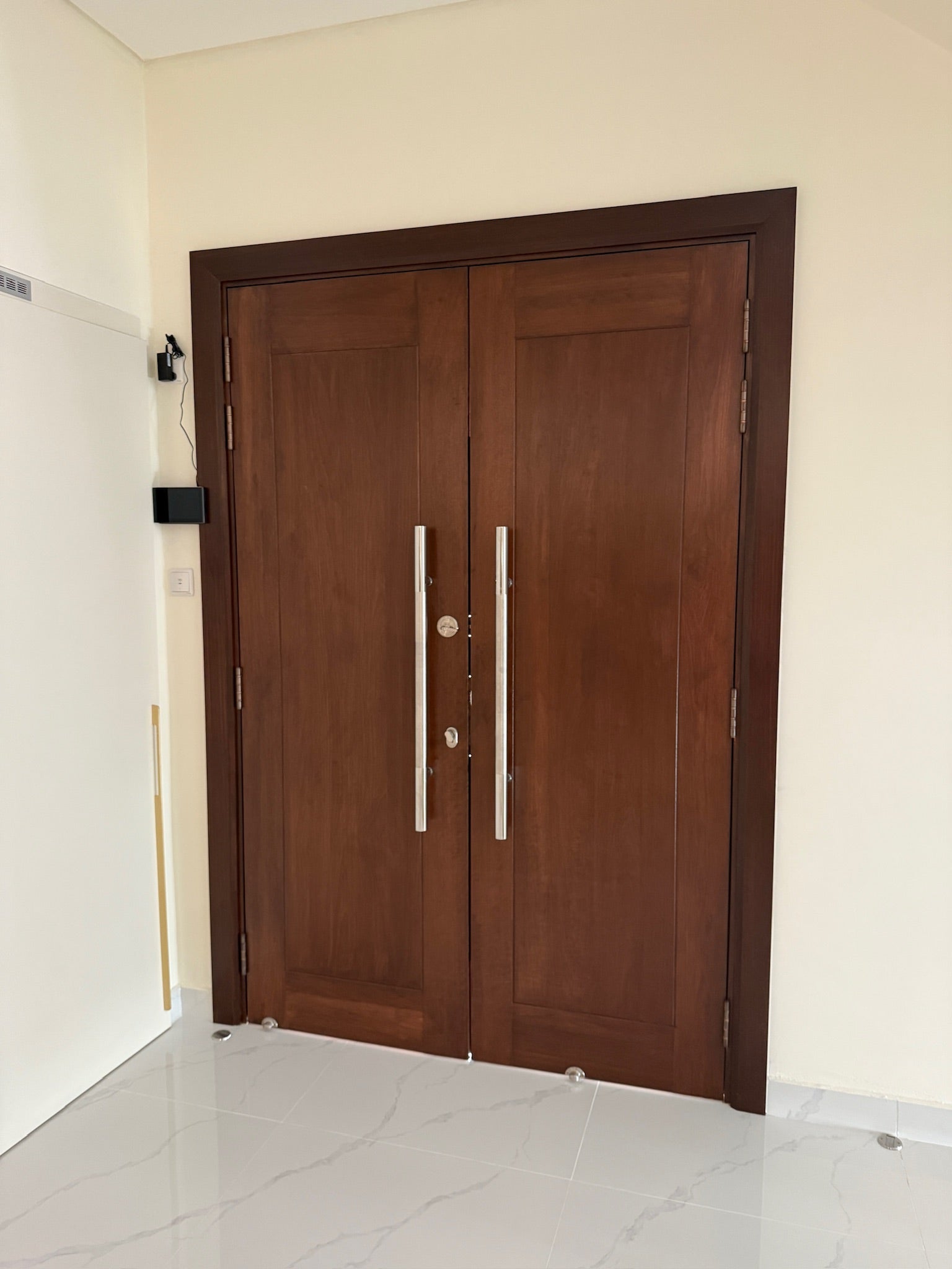 Full solid grade A timber double leaf door made out of nyatoh hardwood, finished with darker stain and installed at the entrance of a house.