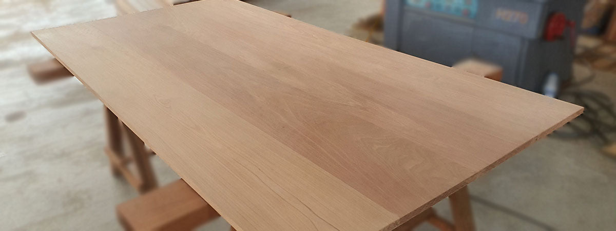 A wooden tabletop made out of nyatoh solid hardwood in a blurred background.